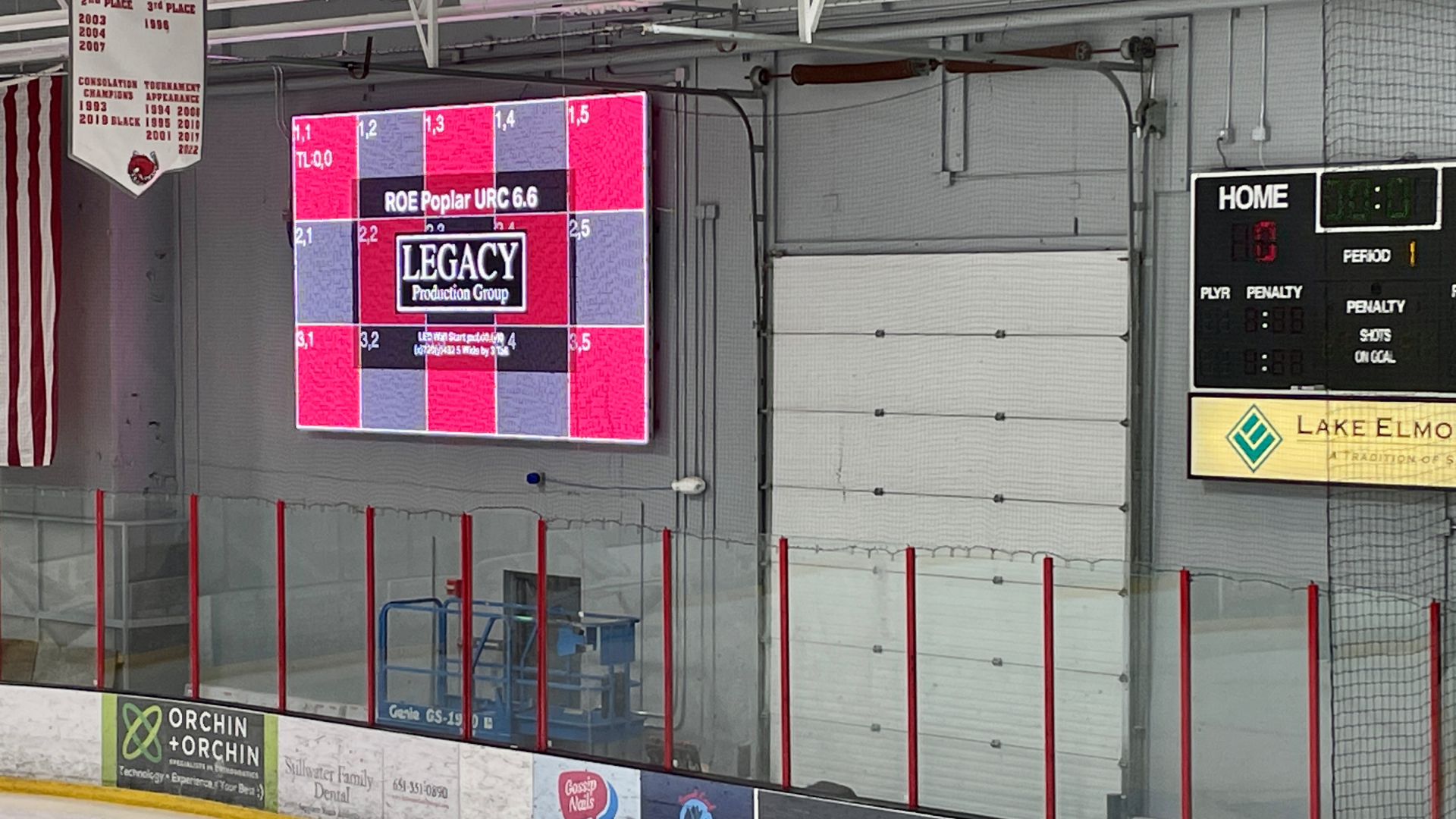 LED Ice Rink Install Live production control room with five operators wearing headsets seated at desks loaded with laptops, video switchers, and audio mixers; two large wall-mounted screens display multi-view camera feeds and a bright studio preview in a carpeted office space